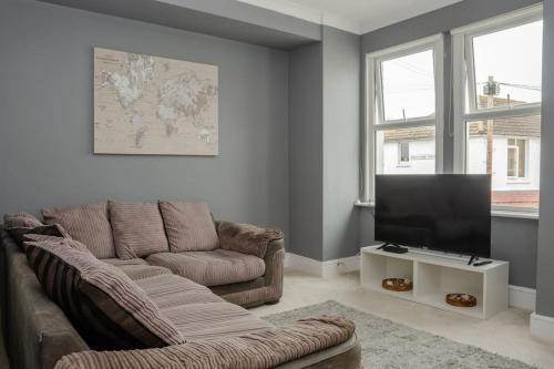 a living room with a couch and a flat screen tv at Peaceful & Spacious Family Home In Eastbourne! in Eastbourne