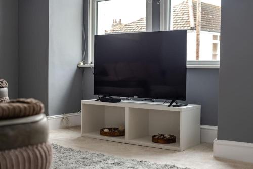 a flat screen tv on a white stand in a living room at Peaceful & Spacious Family Home In Eastbourne! in Eastbourne