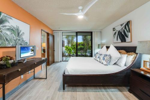 Un dormitorio con una cama con un escritorio y un televisor. en Waikoloa Villas A107, en Waikoloa