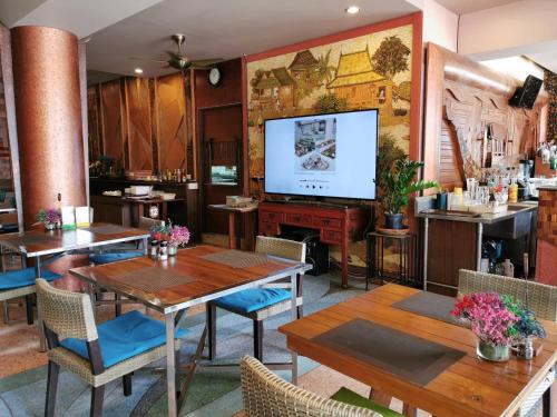 a restaurant with tables and chairs and a large screen at ON Hotel Phuket - SHA in Karon Beach