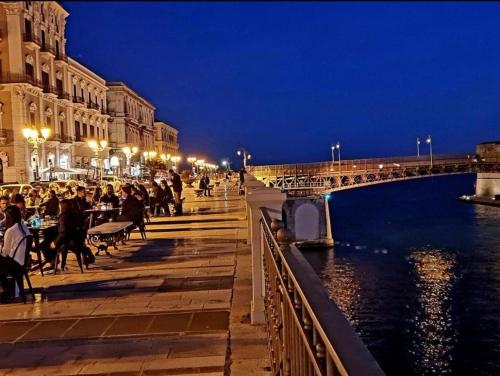 a crowd of people sitting at tables by the water at night at Come nelle favole in Taranto