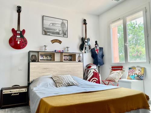 a bedroom with a bed and guitars on the wall at Villa 11 personnes in Saturargues