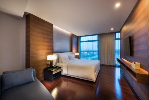 een slaapkamer met een bed en een tv en een bank bij Novotel Shanghai Hongqiao in Shanghai