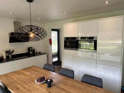 a kitchen with a wooden table and white cabinets at Traum Ferienhaus mit Dachterrasse am Veluwemeer in Hulshorst