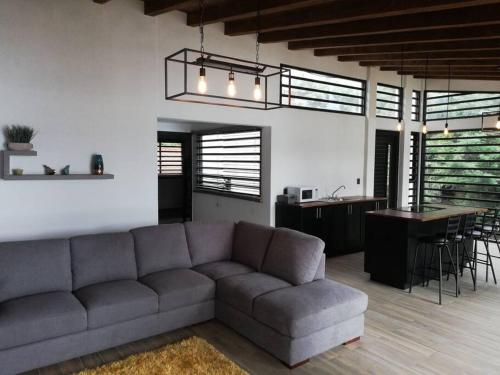 a living room with a couch and a kitchen and a bar at Zirahuen, cabaña moderna junto al lago in Zirahuén