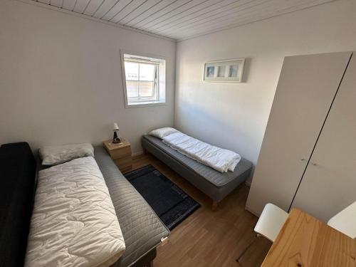 a small bedroom with two beds and a window at Nautnes Seaside Apartments in Nautnes