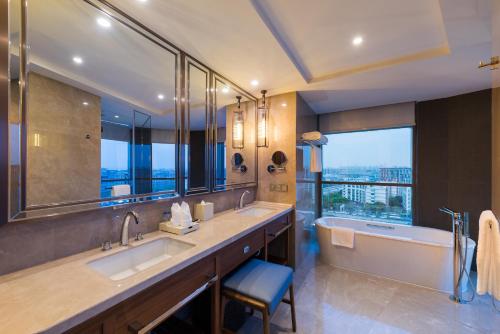 baño con 2 lavabos, bañera y ventana grande en Novotel Shanghai Hongqiao, en Shanghái