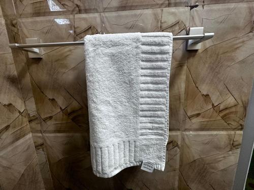 toalla blanca colgada en un toallero en el baño en N Joy Inn, en Trincomalee