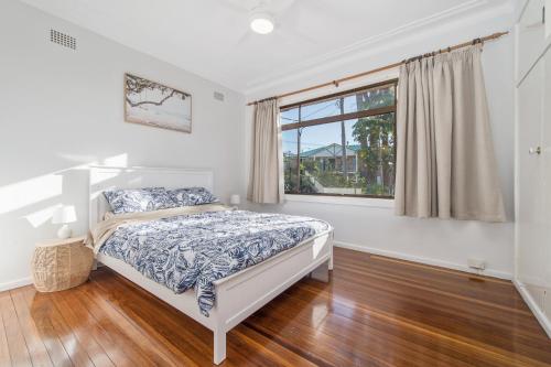 a white bedroom with a bed and a window at Dusties 5 Pacific Street in South West Rocks
