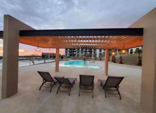 a patio with chairs and a table and a pool at Maralta Condominio con Vista al Mar in Cabo San Lucas