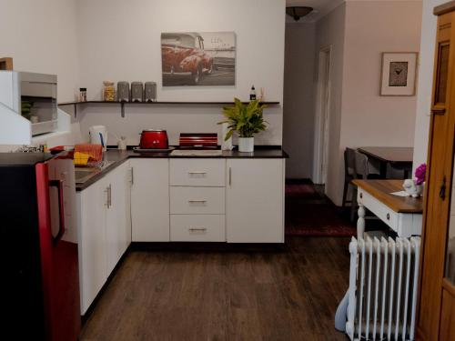 a kitchen with white cabinets and a red car on the wall at Desiderata Cottage in Hilton