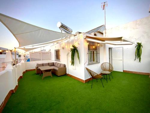un patio con césped verde en un edificio blanco en Casa Castelar by Bossh Apartments, en Rota
