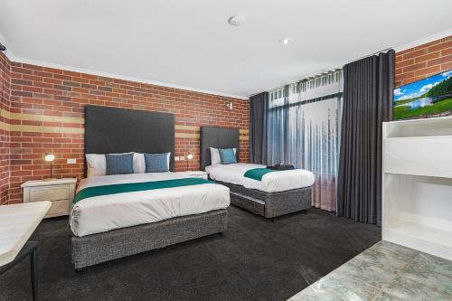 a bedroom with two beds and a brick wall at Rochester Motel in Rochester