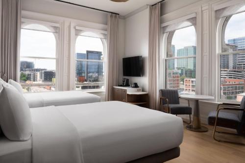a white hotel room with two beds and windows at The Union Station Nashville Yards, Autograph Collection in Nashville
