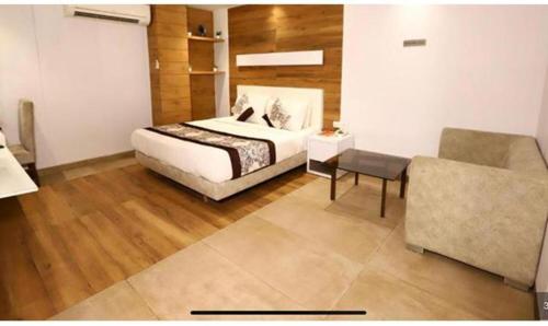 a bedroom with a bed and a couch and a chair at FabHotel Prime Anchorage in New Delhi