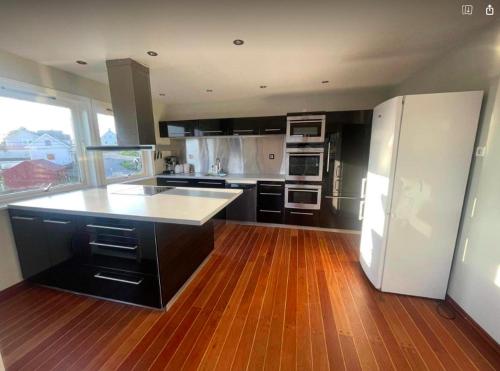 a kitchen with a white refrigerator and a wooden floor at Nautnes Seaside Villa in Nautnes