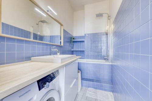 La salle de bains est pourvue de carrelage bleu, d'un lavabo et d'un lave-linge. dans l'établissement Lovely & quiet 1 Bdr Flat at the Luxury 16th Paris, à Paris