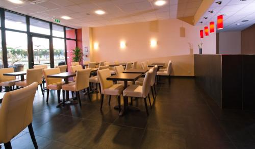 une salle à manger avec tables, chaises et fenêtres dans l'établissement Hotel Eurocentre 2* Toulouse Nord, à Castelnau-dʼEstrétefonds