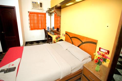 a bedroom with a bed and a vase of flowers on a table at Hotel Sunpark Inn in Chennai