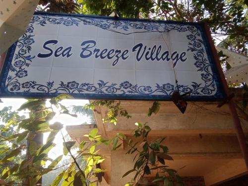 ein Schild für ein Sea Breeze Village an einem Gebäude in der Unterkunft Sea Breeze Village, Baga Goa in Calangute