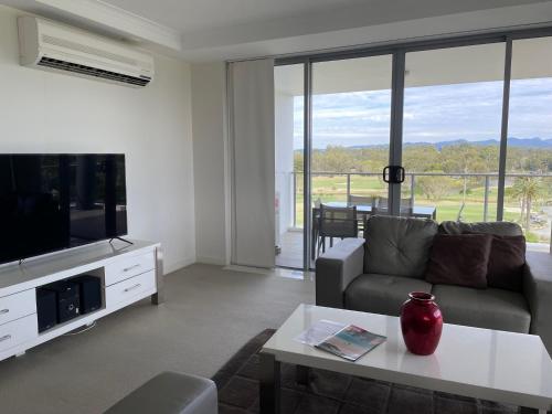 a living room with a couch and a tv and a table at Signature Waterfront Apartments in Gold Coast