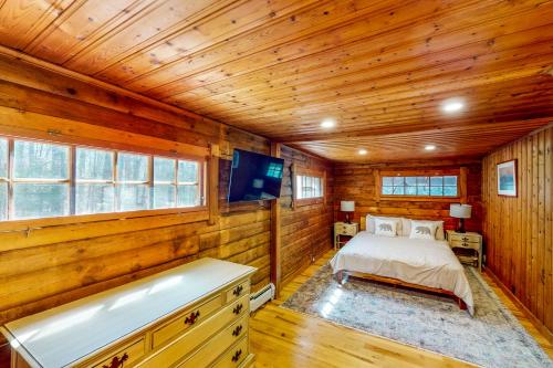 1 dormitorio con cama y bañera en una habitación con paredes de madera en Hawks Eye Cabin, en Otis