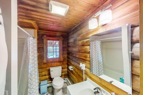 uma casa de banho com paredes de madeira, um WC e um lavatório. em Hawks Eye Cabin em Otis