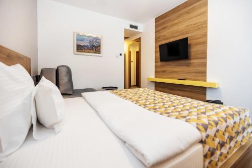a hotel room with a bed and a flat screen tv at Planinka in Kursumlijska Banja