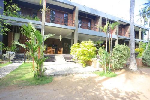 een gebouw met palmbomen ervoor bij Hotel Riverrina in Negombo