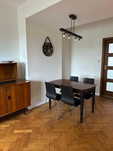 een eettafel met stoelen en een klok aan de muur bij Apartament Syrokomli 3 in Gdynia