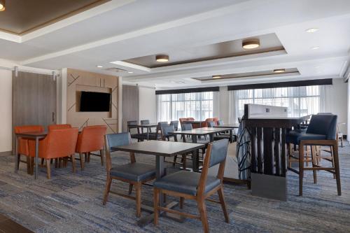 a waiting room with tables and chairs and a tv at Holiday Inn Express & Suites - Kansas City KU Medical Center by IHG in Kansas City