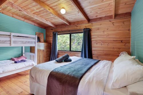 een slaapkamer met houten wanden, een bed en een raam bij The Bower in Merrijig