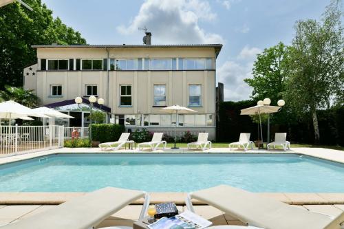 - une piscine avec des chaises et des parasols en face d'un bâtiment dans l'établissement Logis Hôtel & Restaurant Ludik, à Bergerac