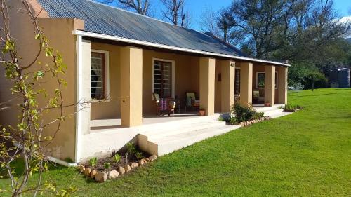 a small house with a porch and a lawn at Aloe Valley Retreat in Oudtshoorn