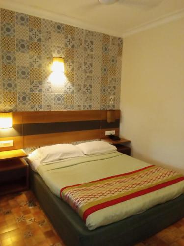 a bedroom with a bed with two lights on the wall at Sea Breeze Inn, Calangute Goa in Calangute