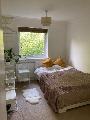 a bedroom with a bed with yellow pillows and a window at Croxley Room with free Parking in Croxley Green