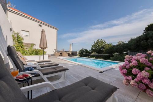 een patio met 2 stoelen en een zwembad bij Mediterranea private pool apartment in Solin