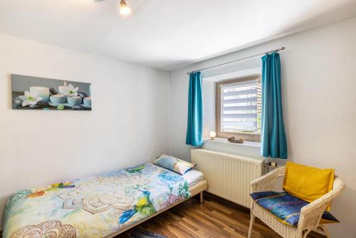 ein Schlafzimmer mit einem Bett, einem Fenster und einem Stuhl in der Unterkunft Alb Rose Ferienwohnung in Sonnenbühl