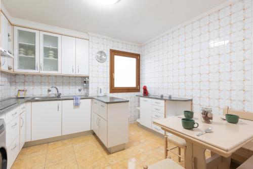 a kitchen with white cabinets and a table at Artibai - baskeyrentals in Ondárroa