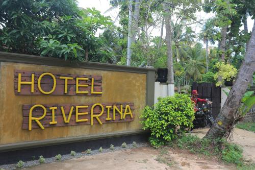 a sign for a hotel rieverma with a man on a motorcycle at Hotel Riverrina in Negombo