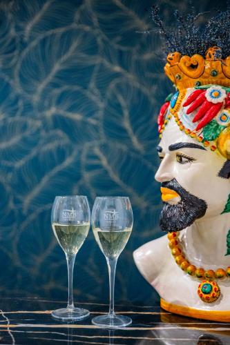 two glasses of white wine next to a statue at Naxos Marina Bay in Giardini Naxos
