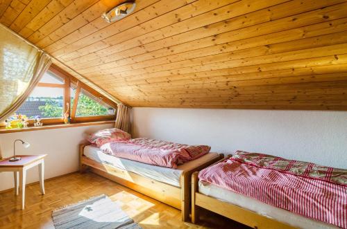 two beds in a room with a wooden ceiling at Rose Garden in Heiligenberg