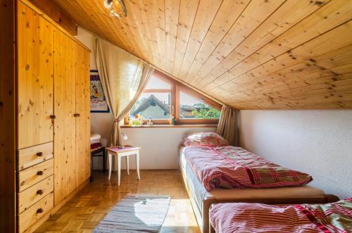 a bedroom with two beds and a wooden ceiling at Rose Garden in Heiligenberg