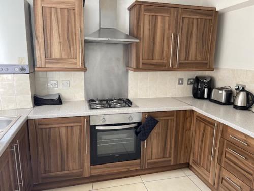 a kitchen with wooden cabinets and a stove top oven at Marks Place in Liverpool