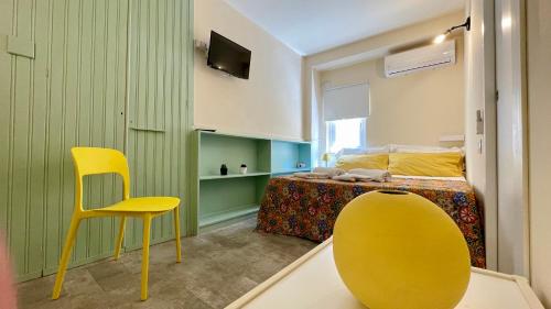um quarto com uma cadeira amarela e uma cama em Portineria 23 em Siracusa