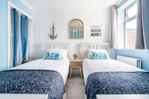 two beds in a room with blue and white at Gorgeous Beach House in Kent