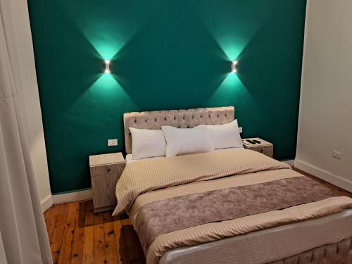 a green bedroom with a bed with two lights on it at downtown Family Suites in Cairo