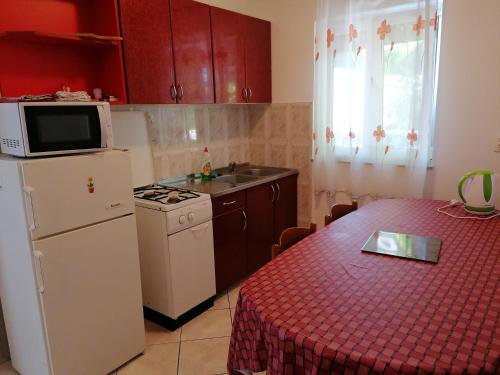 a kitchen with a white refrigerator and a table with a red table cloth at Apartments Villa Venera in Ražanac