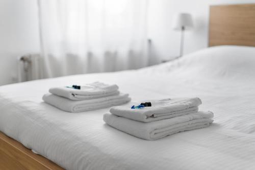 three towels are stacked on a white bed at Villa Maria Villa aan zee met privé parking 8p in Nieuwpoort
