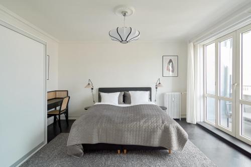 a bedroom with a bed and a table and windows at Beautiful 3 Bedroom Flat Near Shopping & Metro in Copenhagen